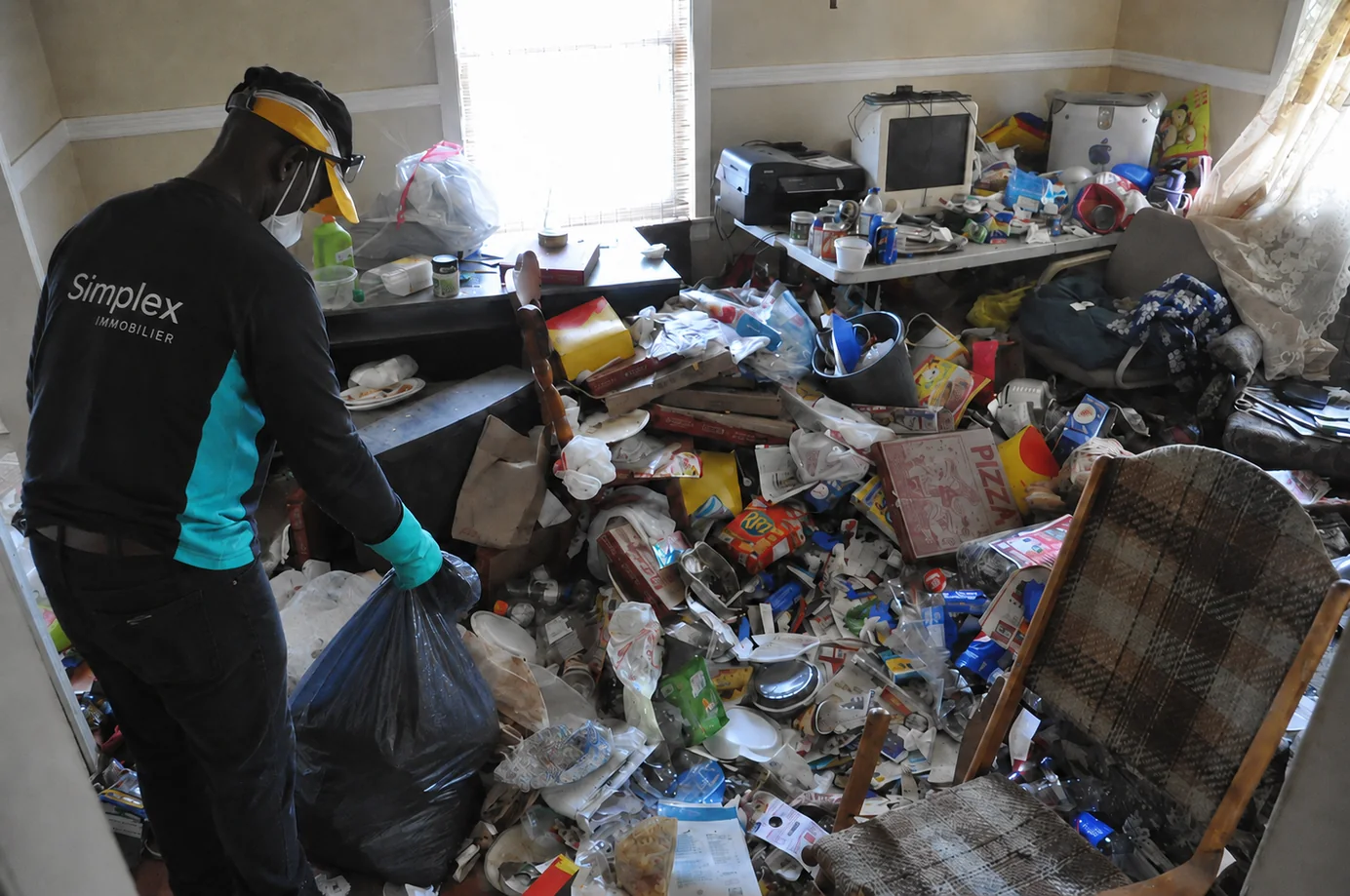 Intervenant Simplex retirant des déchets d’un logement fortement encombré